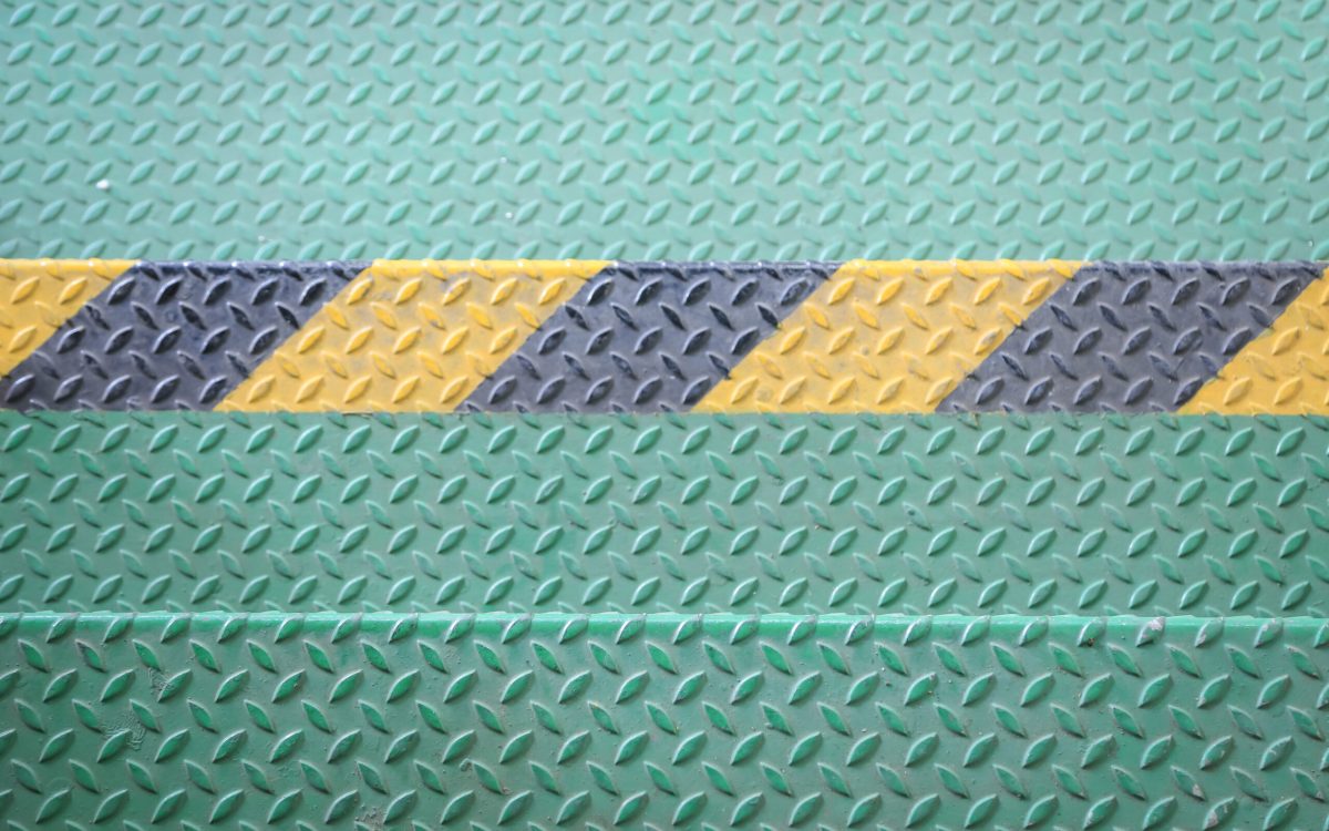 Green metal floor with diamond plate texture and a yellow and black hazard stripe in the center